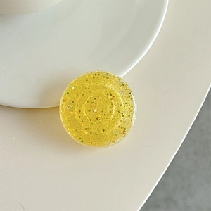 Close-up of a yellow glitter phone grip with colorful sequins and a resin finish