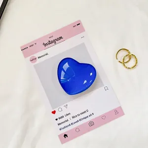 Vista macro di un supporto per telefono a cuore blu lucido e un anello dorato elegante