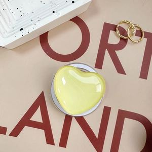 Detail of a pale yellow heart-shaped magnetic phone grip on a stylish prop background