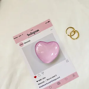 Dettaglio del cuore di vetro rosa e anelli a spirale dorati su carta social media rosa
