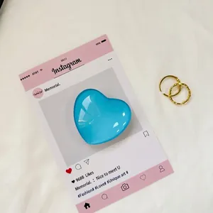 Macro di cuore in vetro blu con due anelli d'oro intrecciati su tessuto bianco