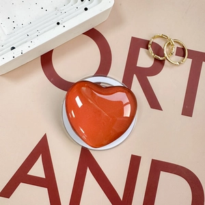Macro detail of glossy orange heart magnetic phone stand with sparkling metallic finish