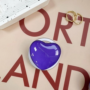 Close-up of a purple heart-shaped phone grip with glitter finish on aesthetic background