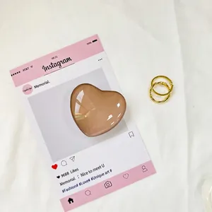 Vista macro di un supporto per telefono a cuore color ambra su sfondo rosa
