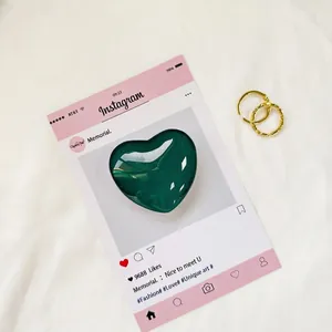 Dettaglio di un supporto per telefono a cuore verde scuro con orecchini a cerchio d'oro