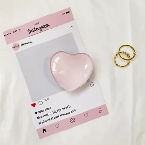 Dettaglio del supporto in cristallo rosa a forma di cuore su fondo di tessuto bianco