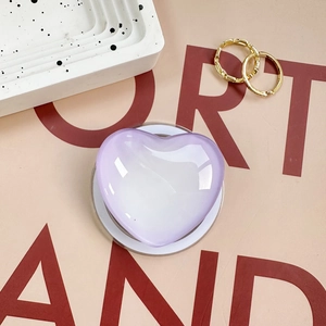 Macro shot of purple heart-shaped magnetic phone grip with acrylic glossy finish on beige background