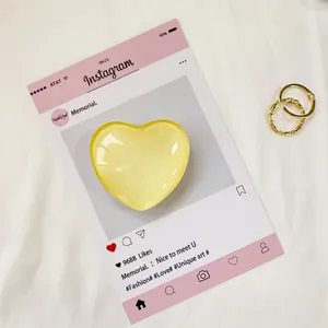 Dettaglio del supporto per telefono a cuore giallo traslucido su carta decorativa social
