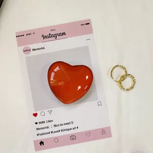 Dettaglio del supporto per telefono a forma di cuore rosso con anelli dorati
