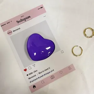 Dettaglio del supporto per telefono a cuore viola lucido su cartolina rosa decorativa
