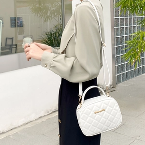 Sac caméra matelassé blanc avec logo doré, poignée supérieure et bandoulière réglable