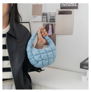 Détail d'un sac à main matelassé bleu clair, texture nuageuse et fermeture éclair arquée