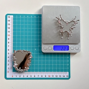 Macro view of silver fluid metal butterfly phone grip showing 22.1g weight and size