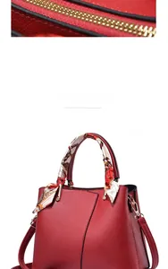 Detailed view of red lychee grain leather handbag with gold zipper and silk scarf handle