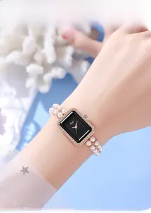 Detail of luxury women's pearl watch featuring a black dial and diamond-encrusted case