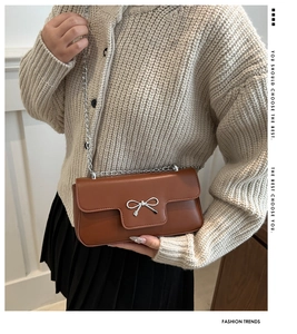 Close-up of brown PU leather bag featuring a silver bow buckle and thin chain strap