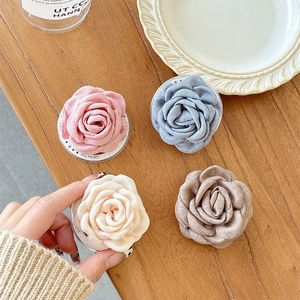 Lot de quatre supports de téléphone en tissu camélia aux tons pastel sur une table