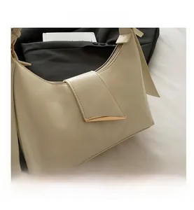 Close-up of minimalist cream underarm bag featuring a smooth texture and gold metal hardware