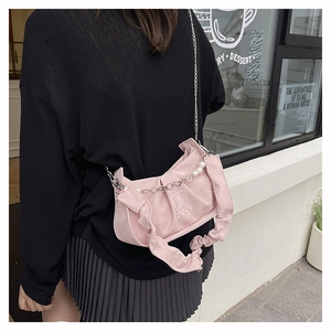 Detailed view of pink pleated handbag with silver chain and pearl strap in street style