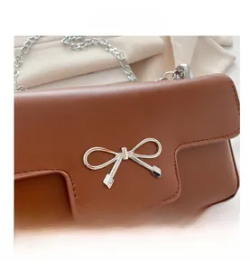 Détail d'un sac en cuir caramel avec boucle noeud en métal argenté et bandoulière
