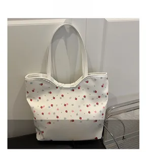 Detail of white canvas tote bag with red strawberry and blue floral print patterns