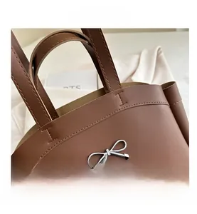 Detailaufnahme der braunen Ledertasche mit silberner Schleife und präzisen Nähten
