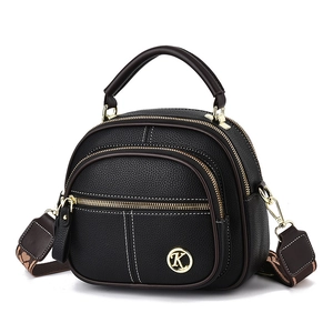 Black pebbled leather crossbody round bag with golden K logo and floral woven strap