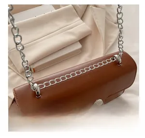 Détail d'un sac bandoulière en cuir marron avec nœud métallique argenté et rabat ondulé