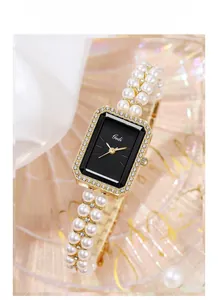 Detail of luxury rectangular watch with black dial and dual-strand pearl bead bracelet