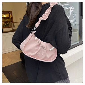 Close-up of pink ruched cloud bag with pearl chain and elegant floral metal charms