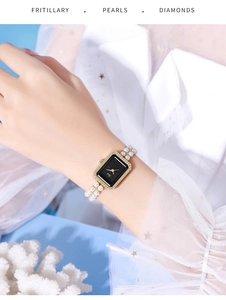 Detailed shot of rectangle gold watch with black dial and double-strand pearl strap