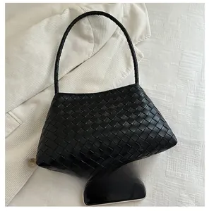 Close-up of black woven leather tote bag texture with mobile phone for size comparison