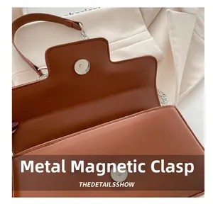 Détail de la fermeture à bouton aimanté en métal sur un sac baguette marron