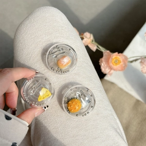 Close-up of clear round acrylic phone grip featuring miniature bread and utensils inside