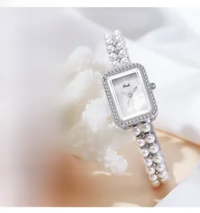 Macro shot of rectangular silver quartz watch with pearl strap and shell dial detail