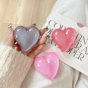 Close-up of glitter heart phone grips in silver, orange, and bright pink resin