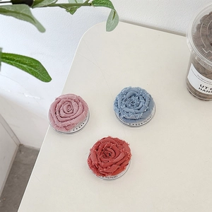 Drie 3D stoffen rozen telefoonhouders in roze, blauw en rood op een tafelblad