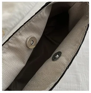 Detailed close-up of a silver magnetic snap button and herringbone fabric lining