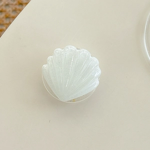 Close-up of pearl white shell-shaped phone grip with shimmering glitter texture