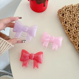Glittery bow-shaped expandable phone grip holder in pink and purple resin colors
