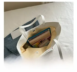 Detail view showing large interior capacity of floral tote bag with items and books