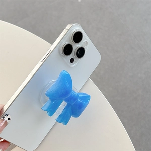 Close-up of a blue glittery bow-shaped collapsible phone grip on a white smartphone