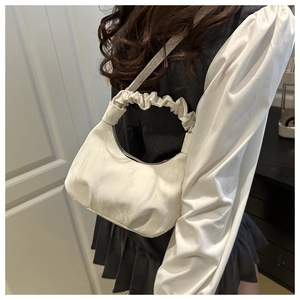 Detail of white dumpling bag showing delicate ruffled shoulder strap and glossy texture