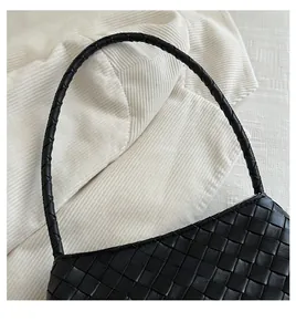 Close-up of premium black woven texture and thick leather handle on a luxury handbag