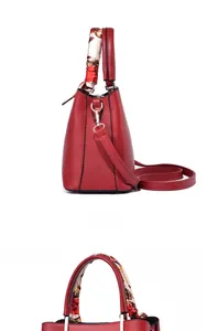 Detail view of red lychee textured leather bag with floral silk scarf handle decoration