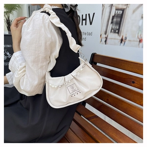 Detail of cream pleated underarm bag with faux pearl chain and ruffled shoulder strap