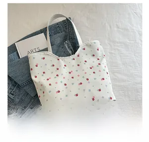 Detailed top-down view of a white floral tote bag with strawberry print and shoulder strap
