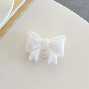 Detail of a white bow-shaped phone grip with pearl finish and transparent socket