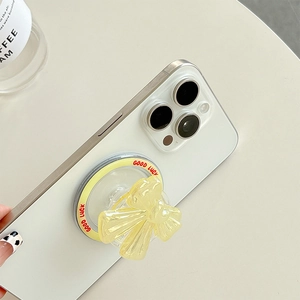 Magnetic yellow bow phone socket grip with Good Luck text on white smartphone