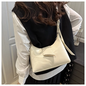 Vue latérale du sac sous les bras minimaliste crème porté par un mannequin